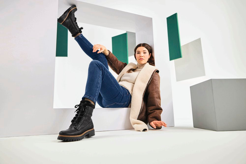lady wearing dark blue skinny jeans tucked into a pair of black laced up ankle boots by Rieker